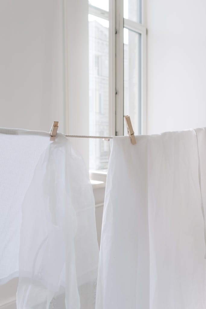 Bright, airy scene of white fabrics hanging on a clothesline indoors, with natural light.